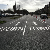 Road with white arrows pointing towards town